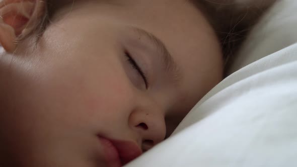 Authentic Cute Little Girl Sleeping Sweetly In Comfortable White and Grey Bed Close Up