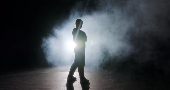 Teenage dancer performing hip hop dance in slow motion with strobe light and smoke background alt