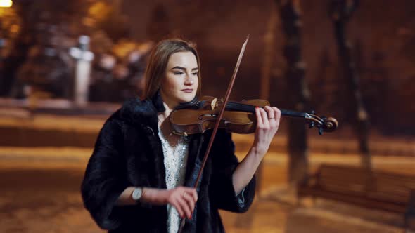 Gorgeous Girl in a Bright Dress and Black Coat Performs Classical Music on a Violin  alt