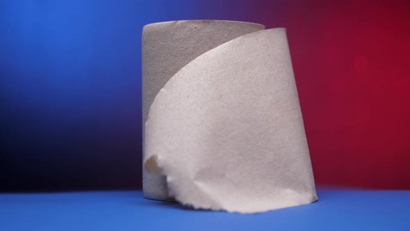 Grey Roll of Toilet Paper on Table Against Blue and Red alt