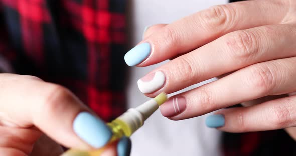 Closeup of female hands with beautiful manicure applying oil to cuticles of fingers alt
