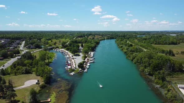 Ascending Aerial backwards shot of niagara river with luxury boats at pier,driving cars on street an alt