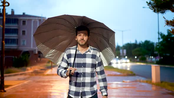 Young Man Walking Through Rainy Weather alt