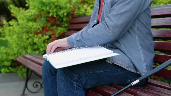 Blind Man Reading Braille Book Sitting on Bench in Summer Park alt