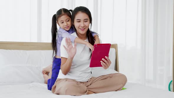 happy mother and little daughter having fun to make technology video call with digital tablet