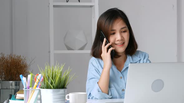 Young Asian business owners using laptops and smart phone at the home office.