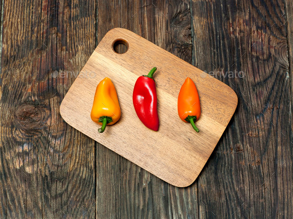 Three peppers on a board.
