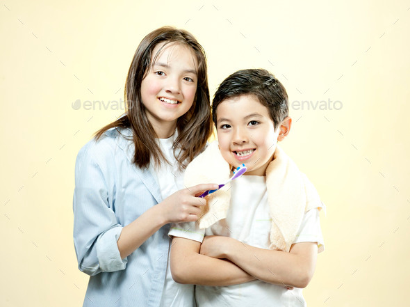 Sister holds toothbrush for brother.