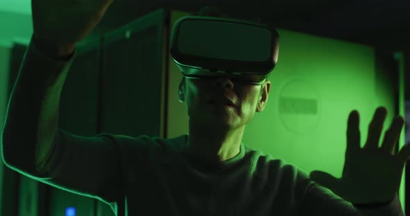 Asian man wearing vr headset by computer server alt