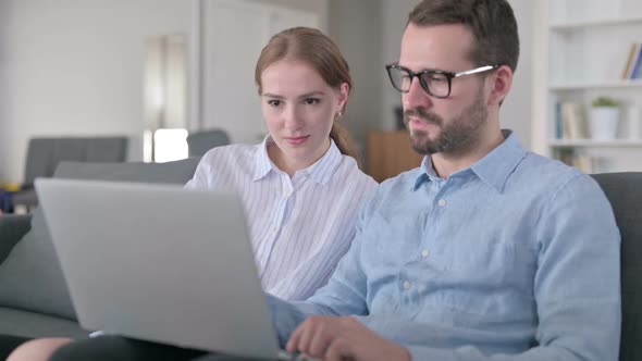 Excited Young Couple Celebrating Success on Laptop at Home alt