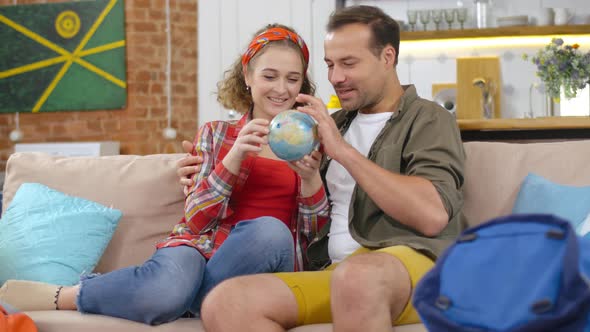 Couple of Young Tourists Looking at Globe Choosing Country alt