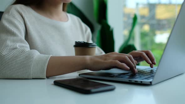 Closeup a woman working and typing on laptop computer keyboard in office