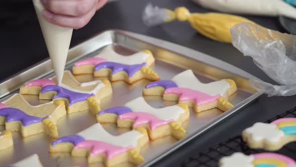 Step by step. Decorating unicorn sugar cookies with royal icing on baking sheet alt