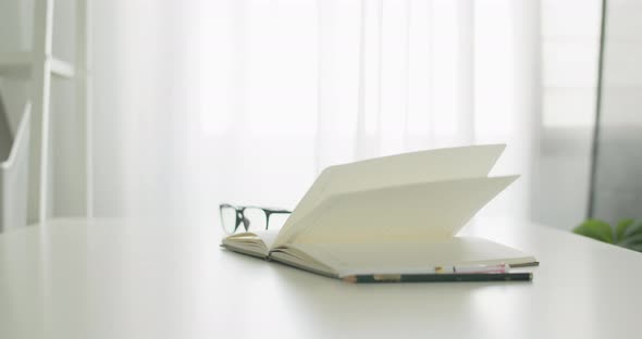 Books pages turning by wind on table in the office room at home. alt