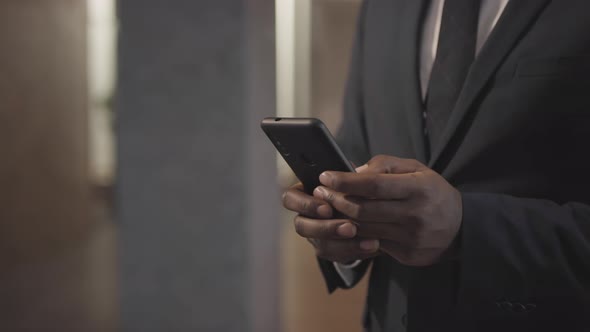 Unrecognizable Businessman Typing on Mobile Phone alt