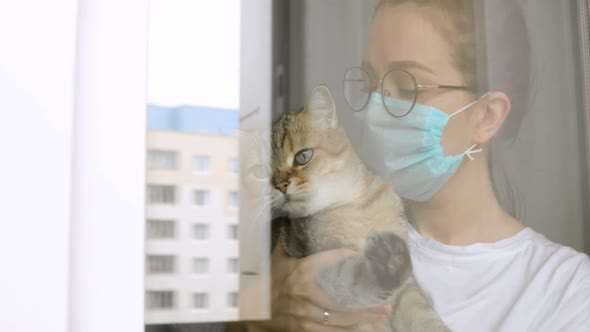 Girl in Mask with Cat Is Missing About Usual Normal Life on Quarantine at Home.