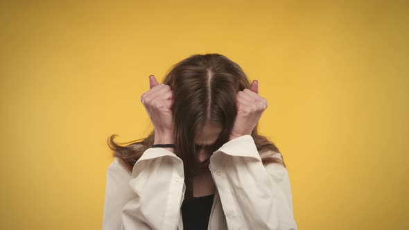 Young Adult Caucasian Woman is Anxious and Taking a Deep Breath on a Bright Yellow Background alt