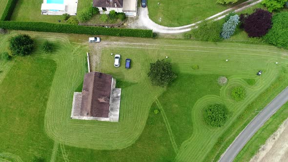 Riding lawn mower in action seen from the sky alt