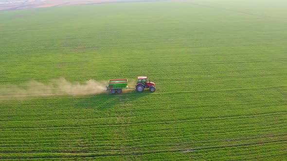Tractor A red tractor against a background of a green field sprays mineral fertilizers.Minera9 alt