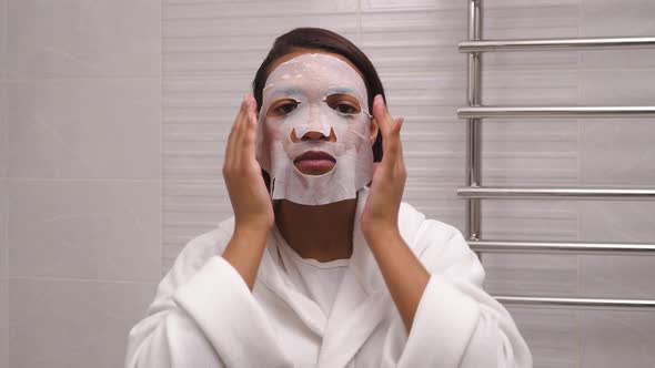 A Young Woman Uses a Cloth Mask to Moisten Her Face