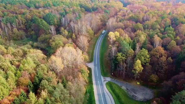 Aerial Shot of a Truck Driving on a Scenic Country Road in Autumn Forest.