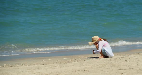 A Funny Little Girl in a Hat on the Seashore Collects Seashells Stars Scallops Shells Kid on the alt