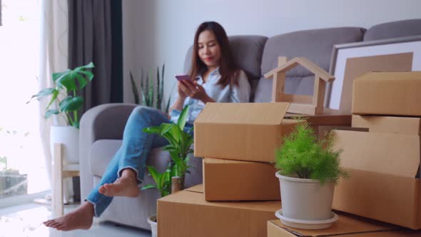 Happy young asian woman using smartphone in living room