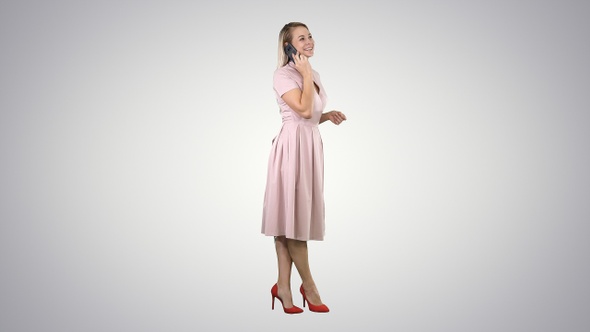 Pretty girl in pink dress on the phone on gradient background. alt