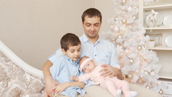 Young father with son and newborn on a sofa in Christmas
