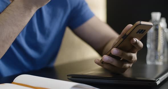 Close-up of Smartphone in Young Male Hand. Unrecognizable Middle Eastern Guy Eating Apple and alt