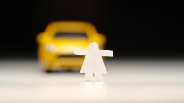 Yellow toy car knocks down a female figure on a road