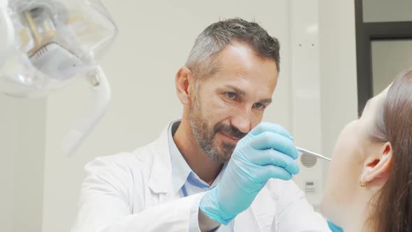 Charming Male Dentist Smiling To the Camera While Working with Patient