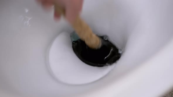Male Hand Cleans Toilet with Plunger of Hand Pump alt