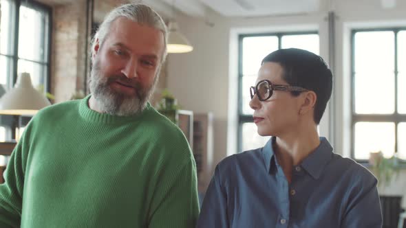 Mature Colleagues Walking in Office and Talking alt