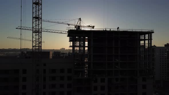 Construction Site at Sunset. Silhouette of a Construction Crane Near the Building