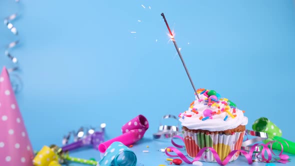Birthday Cake or Cupcake with a Burning Sparkler on a Blue Background