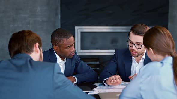 Male mentor speaking to young people in suits teaching audience at business seminar alt