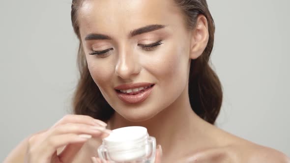 Pretty Girl Holding Cream and Applying It on Her Face alt