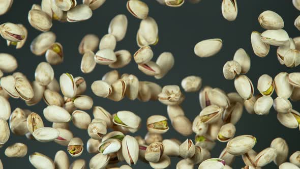 Super Slow Motion Shot of Flying Pistachios After Being Exploded on Grey Background at 1000Fps alt