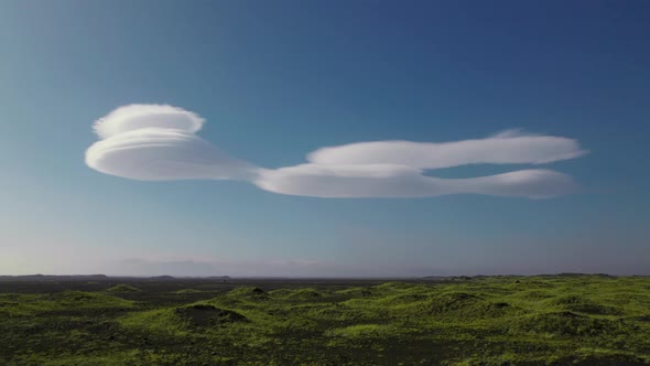 Drone Over Green Landscape Towards Unusual Stratus Clouds In Blue Sky alt