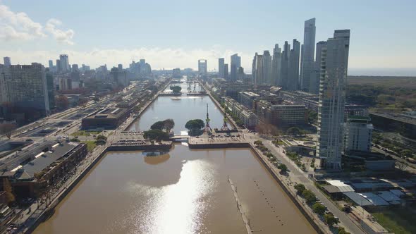 Aerial view flying over Puerto Madero's waterway with some skycrapers at right. Dolly in alt