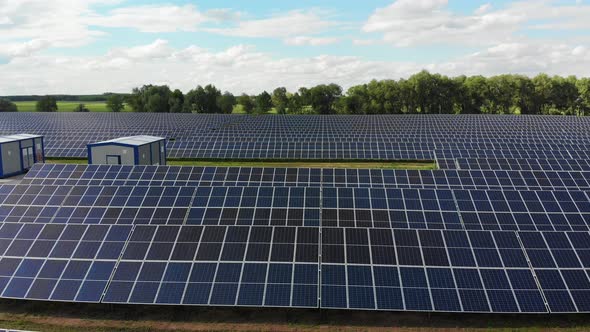Aerial View of Solar Power Station. Panels Stand in a Row on Green Field. Summer alt