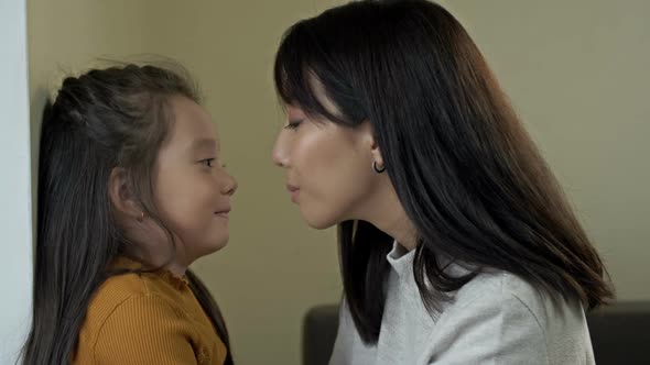 An Asian Mother and Her Little Daughter Gently Touch Each Other's Heads