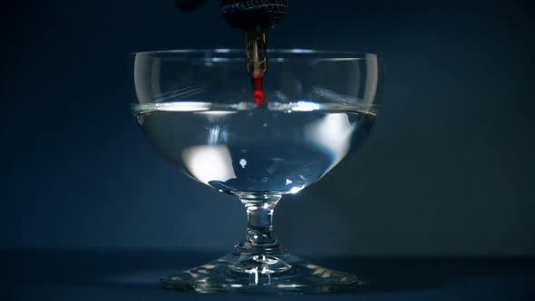 Red Paint Slowly Dissolves In A Glass Of Water. alt