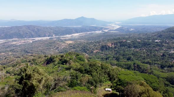 Aerial rising over Jesus Christ statue, large river and mountain ranges in vast wilderness landscape alt