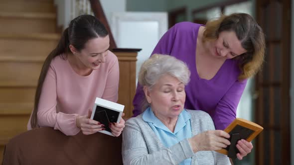 Positive Beautiful Caucasian Senior Woman Telling Stories to Daughter and Granddaughter Looking at alt