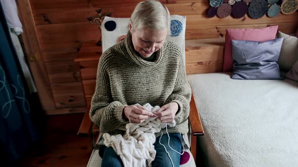 Adult Woman Sits on a Chair Knitting Needles
