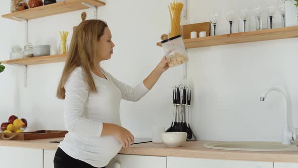 Pregnant Woman in the Kitchen Prepares a Quick Nutritious Breakfast of Cereals alt