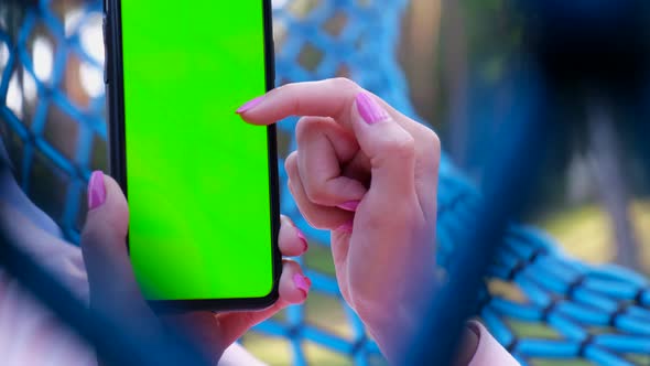 Girl holding a smartphone with a chroma key screen alt