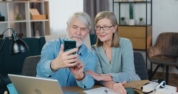 Smiling Mature Couple Using Smartphone for Taking Selfie alt
